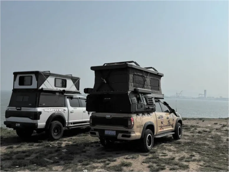 Two pickup trucks fitted with TUYU pop-top campers parked on a beach